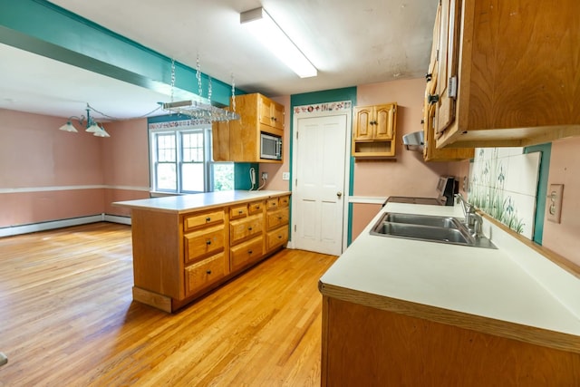 123 S Lincoln St, Keene, NH 03431 - kitchen featuring stainless steel microwave, light wood-style floors, a peninsula, brown cabinetry, and light countertops