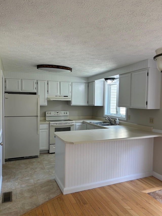 1555 Bodwell Rd Unit 59, Manchester, NH 03109 - kitchen with white appliances, under cabinet range hood, light countertops, a peninsula, and a textured ceiling