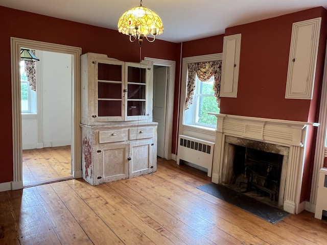 249 Ward Rd, Poultney, VT 05764 - unfurnished dining area with radiator, light wood-style flooring, a premium fireplace, and a chandelier