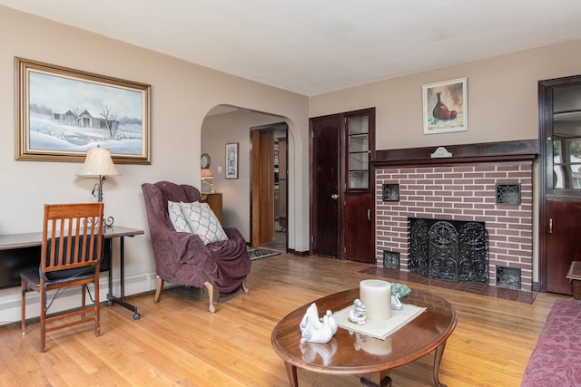 3 Mooreland Ave, Concord, NH 03301 - living room with wood finished floors, arched walkways, a brick fireplace, and a baseboard heating unit