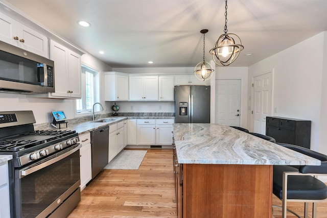 116 Sullivan Center Rd, Gilsum, NH 03448 - kitchen with appliances with stainless steel finishes, a kitchen island, light wood-type flooring, a breakfast bar area, and light stone counters