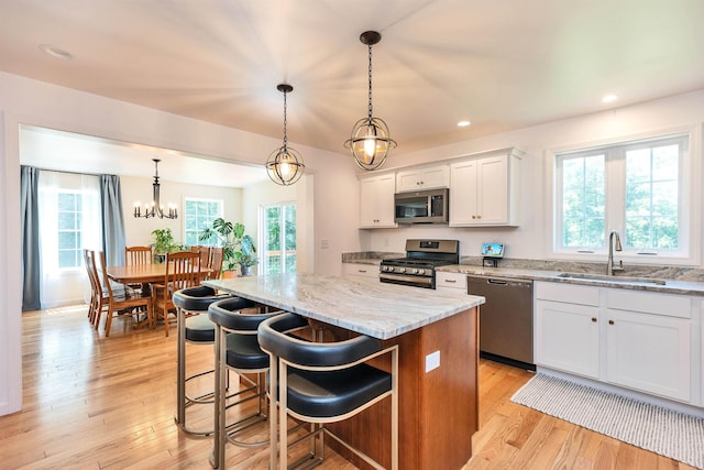 116 Sullivan Center Rd, Gilsum, NH 03448 - kitchen featuring stainless steel appliances, a center island, light stone counters, light wood-style floors, and white cabinets