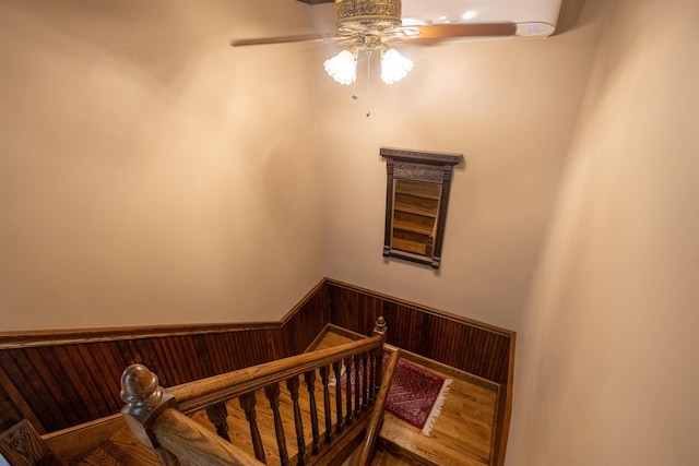 185 Huntress Bridge Rd, Effingham, NH 03882 - staircase featuring a ceiling fan, a wainscoted wall, wood finished floors, and wooden walls