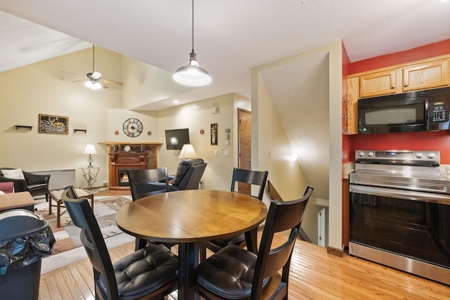 6 Cumberland Rd Unit 12, Gilford, NH 03249 - dining room with light wood-type flooring, a warm lit fireplace, ceiling fan, and lofted ceiling