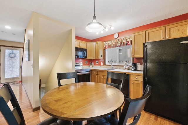 6 Cumberland Rd Unit 12, Gilford, NH 03249 - kitchen featuring black appliances, light wood-style flooring, light countertops, light brown cabinetry, and decorative light fixtures