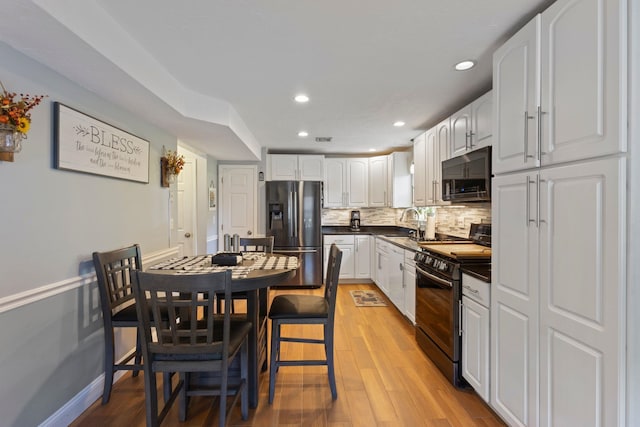 13 Rangers Dr Unit B, Hudson, NH 03051 - kitchen featuring stainless steel appliances, dark countertops, white cabinetry, decorative backsplash, and light wood-style flooring