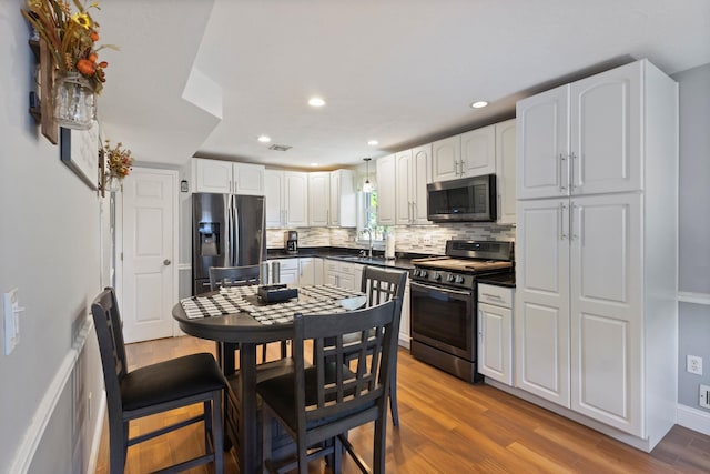 13 Rangers Dr Unit B, Hudson, NH 03051 - kitchen featuring stainless steel appliances, dark countertops, tasteful backsplash, wood finished floors, and white cabinets