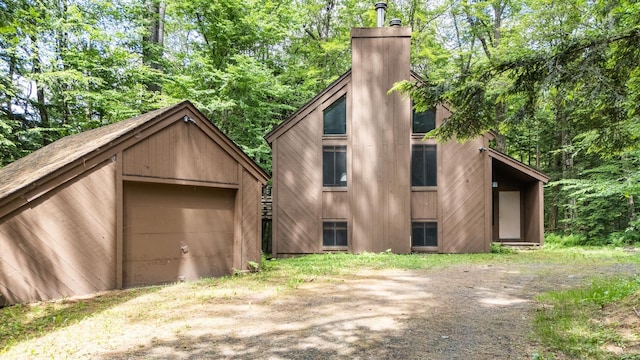 49 Longwood Dr, Grantham, NH 03753 - view of property exterior featuring a chimney, dirt driveway, an outdoor structure, and a detached garage