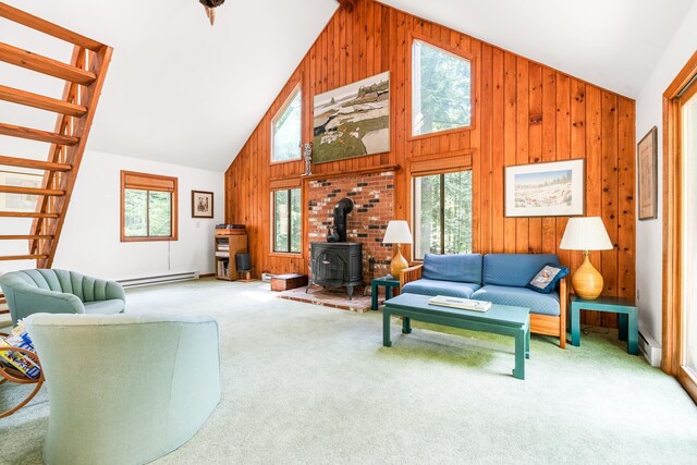 49 Longwood Dr, Grantham, NH 03753 - carpeted living room with a wood stove, a baseboard heating unit, high vaulted ceiling, wood walls, and stairway