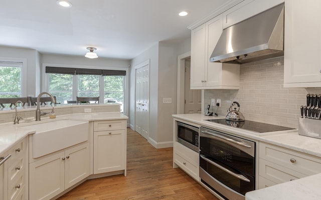 81 Summit Ridge Dr, Keene, NH 03431 - kitchen with wall chimney exhaust hood, appliances with stainless steel finishes, tasteful backsplash, light wood-style flooring, and recessed lighting