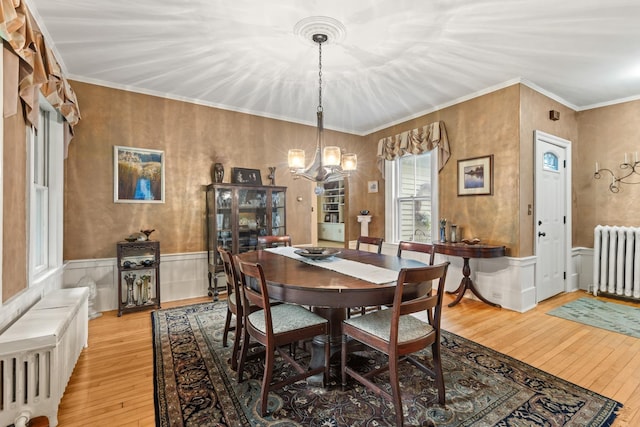 223 Atlantic Ave, North Hampton, NH 03862 - dining space with radiator, light wood-style floors, a chandelier, a wainscoted wall, and ornamental molding