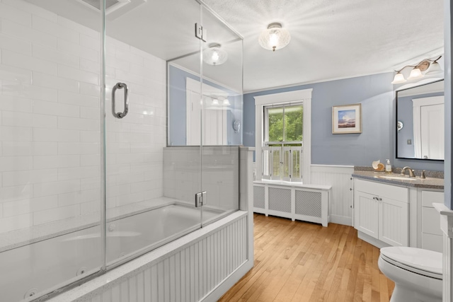 223 Atlantic Ave, North Hampton, NH 03862 - bathroom featuring radiator, hardwood / wood-style floors, tiled shower / bath combo, vanity, and a wainscoted wall