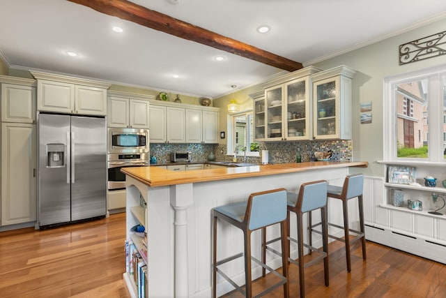 223 Atlantic Ave, North Hampton, NH 03862 - kitchen featuring appliances with stainless steel finishes, ornamental molding, decorative backsplash, light wood finished floors, and a peninsula