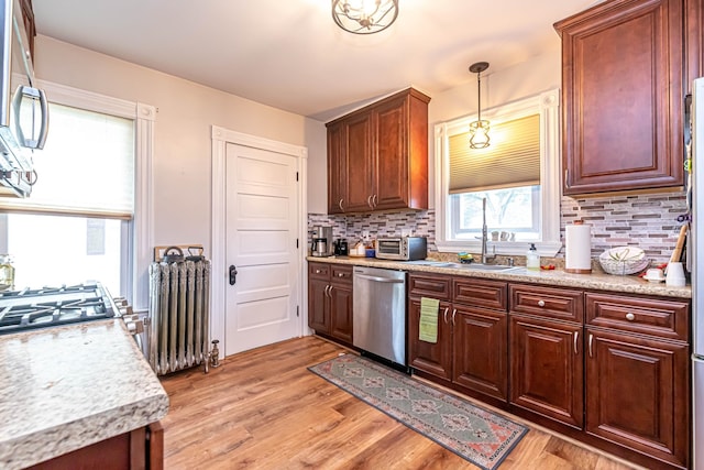 1076 Merrill St, Manchester, NH 03103 - kitchen featuring stainless steel dishwasher, radiator heating unit, light wood-style flooring, and backsplash