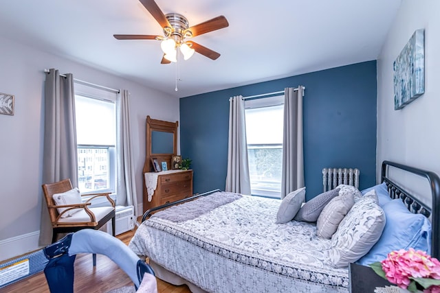 1076 Merrill St, Manchester, NH 03103 - bedroom featuring multiple windows, radiator heating unit, light wood-style floors, and a ceiling fan