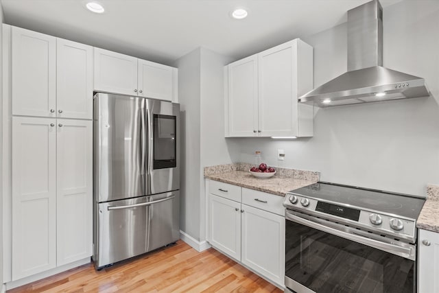 16 Daniels Dr, Lee, NH 03861 - kitchen featuring appliances with stainless steel finishes, wall chimney range hood, white cabinets, light wood finished floors, and light stone countertops