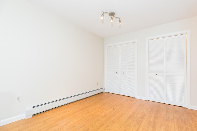 703 Springbrook Cir, Portsmouth, NH 03801 - unfurnished bedroom with a baseboard radiator, multiple closets, and light wood-style floors