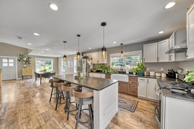 86 Chestnut St, Claremont, NH 03743 - kitchen featuring appliances with stainless steel finishes, wall chimney range hood, healthy amount of natural light, recessed lighting, and light wood-type flooring