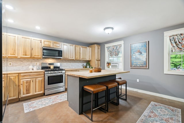 153 May St, Canaan, NH 03741 - kitchen featuring appliances with stainless steel finishes, light brown cabinets, finished concrete floors, a kitchen bar, and a center island