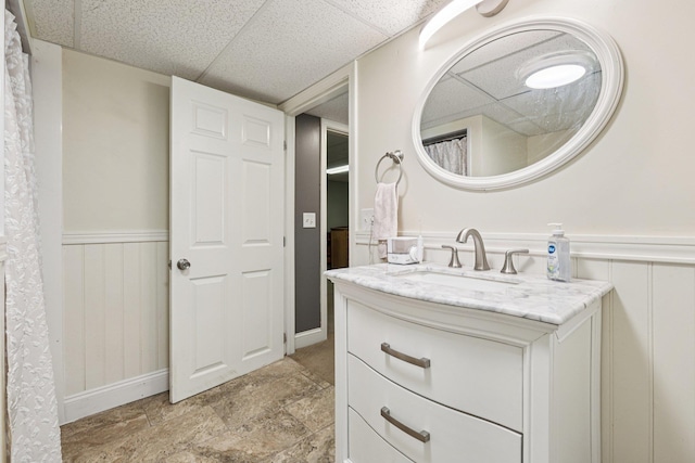 20 Meadow Ln, Atkinson, NH 03811 - bathroom featuring vanity, a wainscoted wall, stone finish flooring, and a drop ceiling