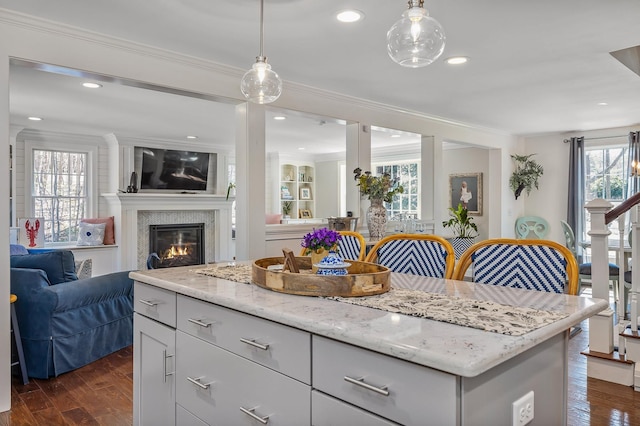23 Rockrimmon Rd, North Hampton, NH 03862 - kitchen featuring open floor plan, ornamental molding, dark wood-type flooring, a glass covered fireplace, and hanging light fixtures