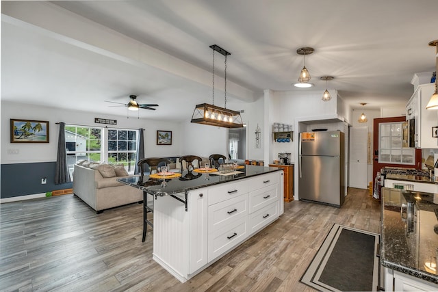 638 Benton Dr, Laconia, NH 03246 - kitchen with freestanding refrigerator, a breakfast bar area, a ceiling fan, wood finished floors, and white cabinets