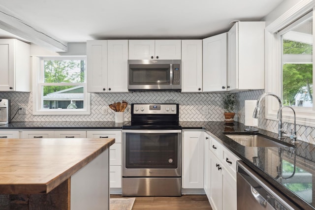 161 Micah Ter, Milton, NH 03851 - kitchen with appliances with stainless steel finishes, white cabinetry, healthy amount of natural light, and decorative backsplash