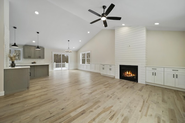 172 Tasker Hill Rd, Strafford, NH 03884 - unfurnished living room featuring a fireplace, a ceiling fan, a chandelier, light wood-style floors, and a wainscoted wall