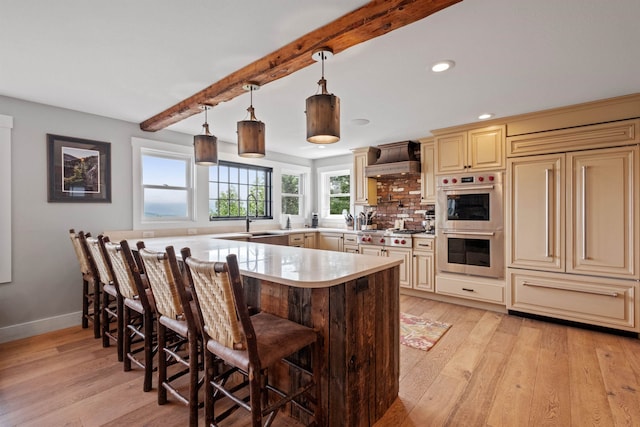 15 Glade Cir, Campton, NH 03223 - kitchen with cream cabinetry, custom exhaust hood, appliances with stainless steel finishes, a breakfast bar area, and beamed ceiling