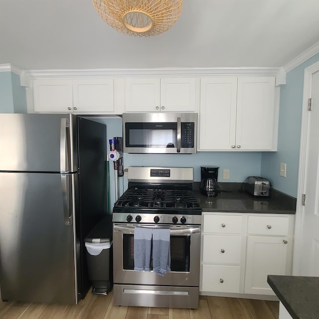 14 Johnson Ave Unit A, Hampton, NH 03842 - kitchen featuring appliances with stainless steel finishes, dark countertops, white cabinets, ornamental molding, and light wood-type flooring