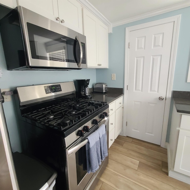 14 Johnson Ave Unit A, Hampton, NH 03842 - kitchen featuring stainless steel appliances, light wood-style floors, crown molding, dark countertops, and white cabinets