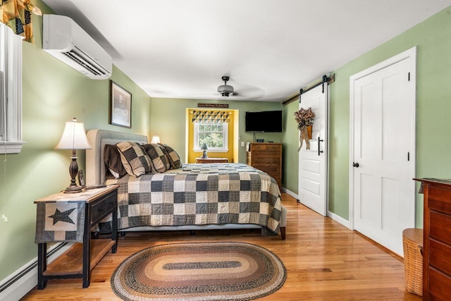 9 Jade Rd, Merrimack, NH 03054 - bedroom with an AC wall unit, wood finished floors, a barn door, and a ceiling fan