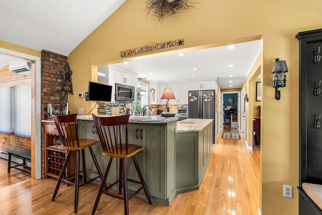 9 Jade Rd, Merrimack, NH 03054 - kitchen featuring appliances with stainless steel finishes, a wall mounted air conditioner, white cabinets, a peninsula, and light wood-style flooring