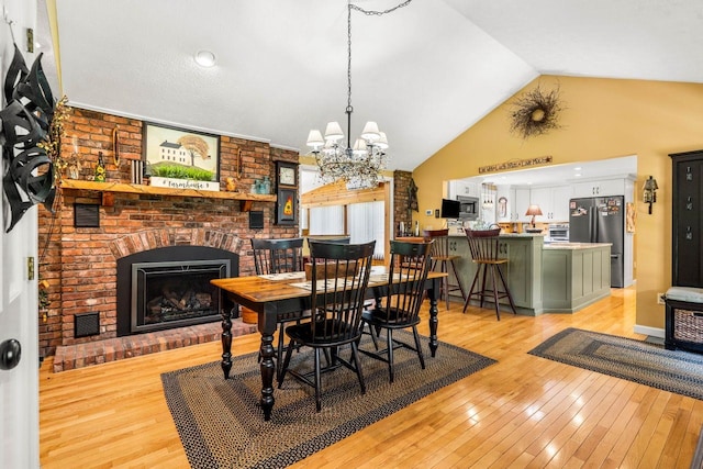 9 Jade Rd, Merrimack, NH 03054 - dining room featuring light wood-type flooring, a brick fireplace, a chandelier, and high vaulted ceiling
