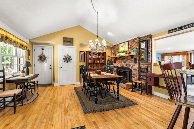 9 Jade Rd, Merrimack, NH 03054 - dining room featuring a chandelier, light wood finished floors, vaulted ceiling, and a brick fireplace