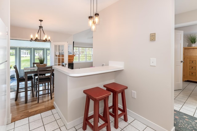 5 Golf Vw Unit B, Laconia, NH 03246 - kitchen featuring light tile patterned floors, a chandelier, a breakfast bar area, decorative light fixtures, and a peninsula