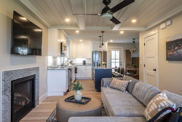 109 Weirs Blvd Unit 9, Laconia, NH 03246 - living area featuring light wood-style floors, ceiling fan, a wood ceiling with exposed beams, ornamental molding, and a glass covered fireplace