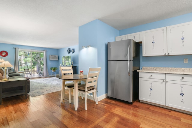 2 Autumn Leaf Dr Unit 20, Nashua, NH 03060 - kitchen featuring freestanding refrigerator, open floor plan, light wood finished floors, white cabinetry, and a wall unit AC