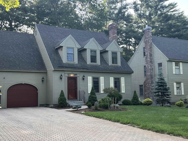 27 Olde Common Dr, Atkinson, NH 03811 - cape cod house featuring driveway, an attached garage, a front yard, a chimney, and a shingled roof
