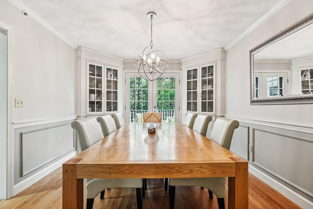 27 Olde Common Dr, Atkinson, NH 03811 - dining space with a chandelier, a decorative wall, crown molding, light wood finished floors, and a wainscoted wall