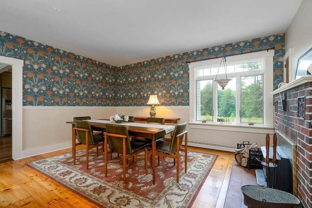 49 Mason Rd, Brookline, NH 03033 - dining area with a baseboard heating unit, wainscoting, light wood-style floors, a brick fireplace, and wallpapered walls