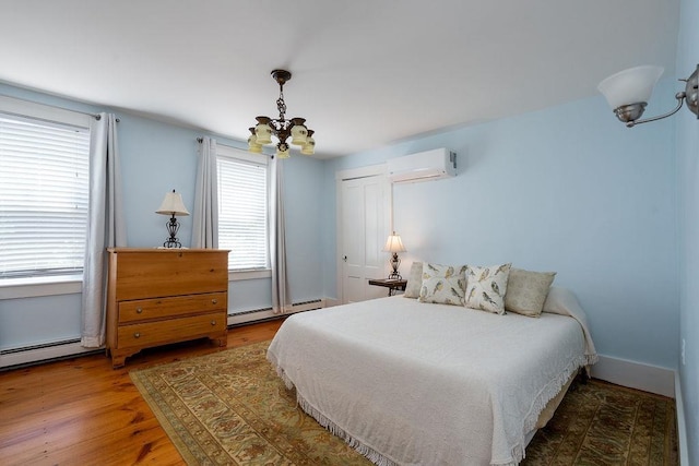 49 Mason Rd, Brookline, NH 03033 - bedroom with a chandelier, a wall mounted AC, a baseboard radiator, and wood finished floors