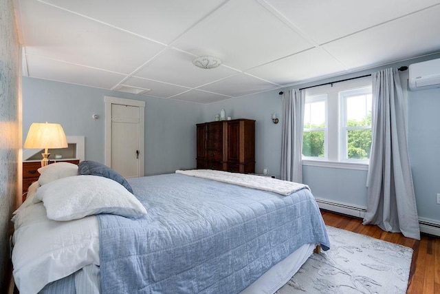 49 Mason Rd, Brookline, NH 03033 - bedroom with a baseboard heating unit, wood finished floors, and a wall mounted air conditioner