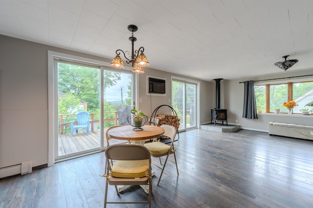 15 Prospect St, Farmington, NH 03835 - dining area featuring a wood stove, wood finished floors, a wall mounted air conditioner, a baseboard radiator, and a chandelier