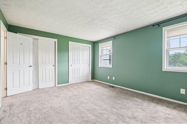 272 Winding Pond Rd Unit 272, Londonderry, NH 03053 - unfurnished bedroom featuring two closets, carpet floors, and a textured ceiling