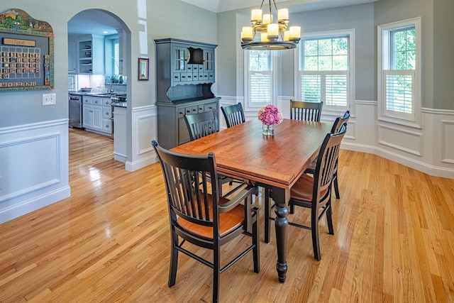 1 Sonia Dr, Dover, NH 03820 - dining room featuring arched walkways, a chandelier, light wood-style flooring, a wainscoted wall, and a decorative wall
