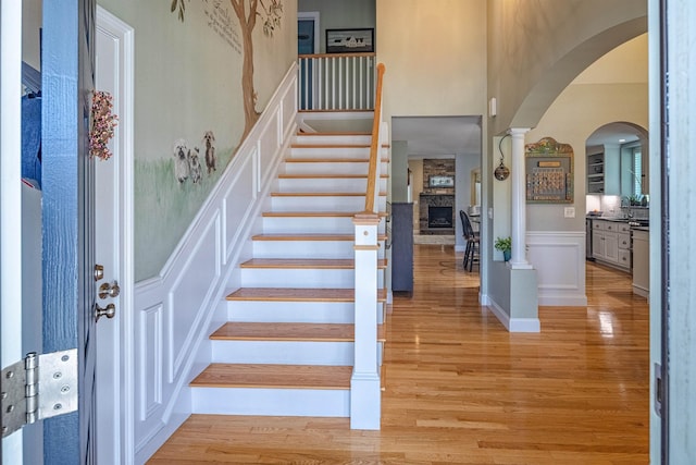 1 Sonia Dr, Dover, NH 03820 - stairs with arched walkways, wood finished floors, a fireplace, a towering ceiling, and decorative columns