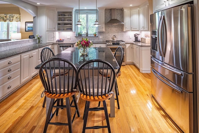 1 Sonia Dr, Dover, NH 03820 - kitchen featuring appliances with stainless steel finishes, wall chimney range hood, light wood-style floors, decorative backsplash, and recessed lighting