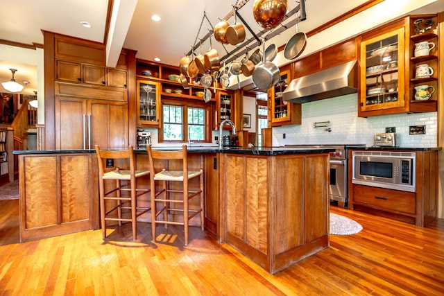 109 Reserve Pl, Concord, NH 03301 - kitchen with ventilation hood, built in appliances, light wood-type flooring, dark countertops, and decorative backsplash