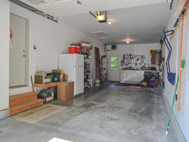 138 Page Rd, New London, NH 03257 - garage featuring freestanding refrigerator and a garage door opener
